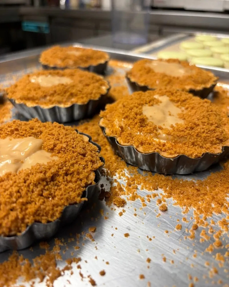 Tartlets with Biscoff crumble and a dollop of cream on a tray.