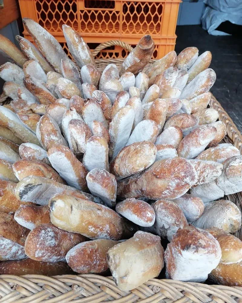 Ein geflochtener Korb voller bemehlter Baguettes am Stand von Le Brot auf dem Bötzowmarkt.