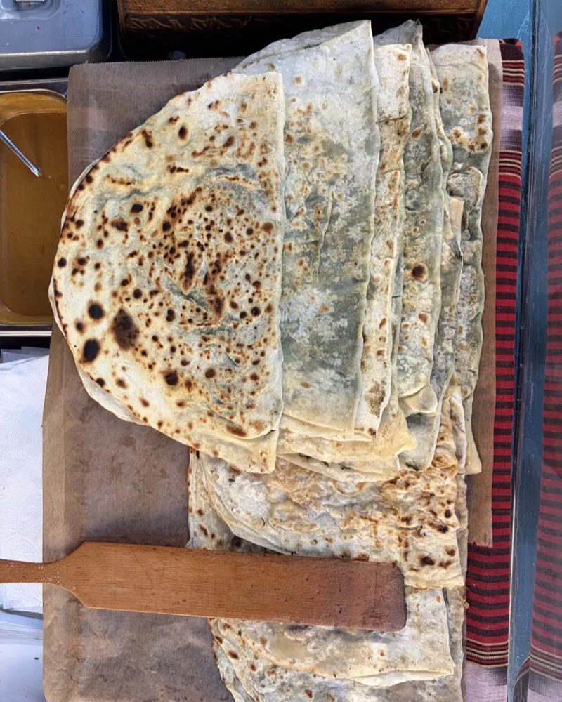 Stacked, freshly baked flatbreads (gözleme) on paper at the 61Bites stall at the Bötzowmarkt.
