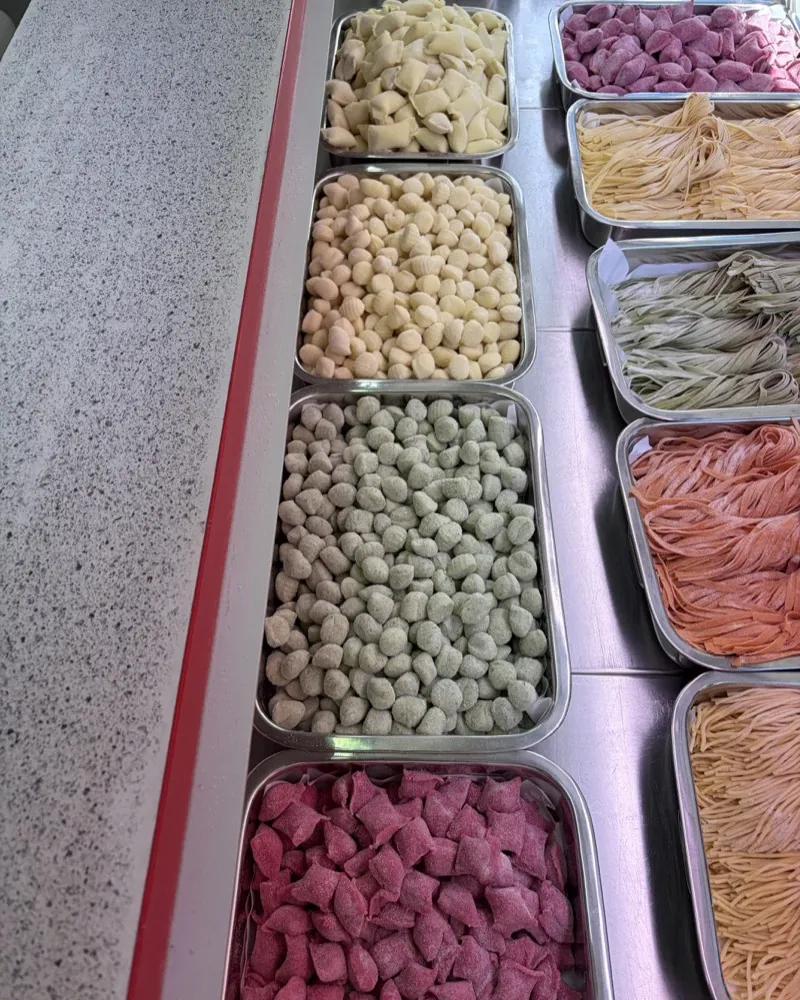Fresh pasta in many colours in stainless-steel trays at the Pasta e Più stall at the Bötzowmarkt: gnocchi, tagliatelle and filled pasta.