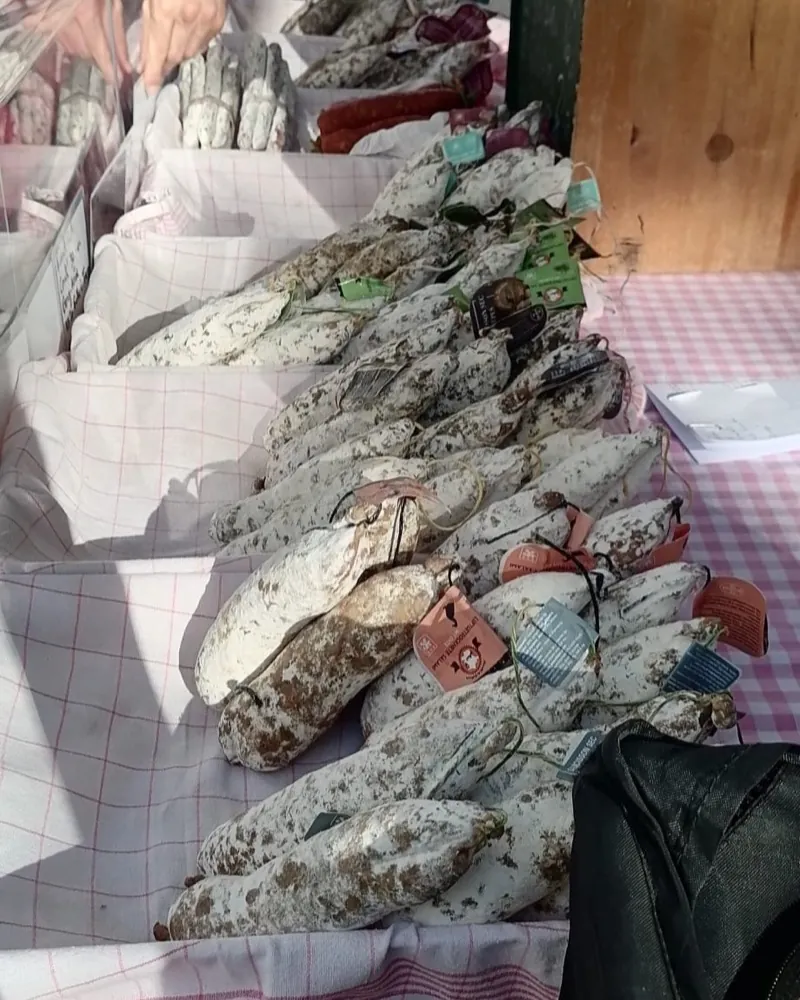 Luftgetrocknete Salamis in Papierkisten auf einer karierten Decke, am Salamistand auf dem Bötzowmarkt.